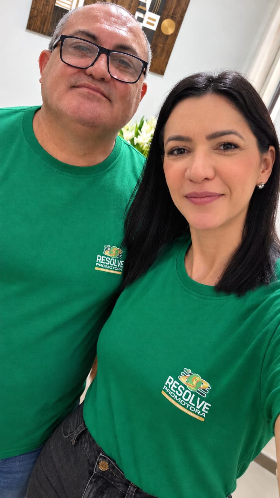 Fundadora da Resolve Promotora ao lado do esposo, ambos com a camisa verde da empresa